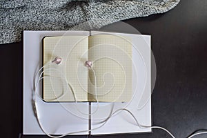 Blank open address notebook on a blank open book with a white headsets and a knitted sweater