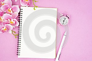 The blank open notebook and clock with pink color orchid for your text or message
