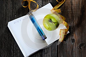 Blank open notebook with green apple and yellow centimeter tape. Concept sport, diet, fitness, healthy eating