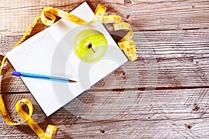 Blank open notebook with green apple and yellow centimeter tape. Concept sport, diet, fitness, healthy eating