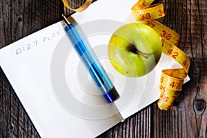 Blank open notebook with green apple and yellow centimeter tape. Concept sport, diet, fitness, healthy eating