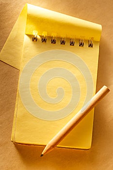 Blank open yellow notepad with pencil