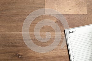 Blank page of an agenda in Spanish for the month of January, on a wooden desk