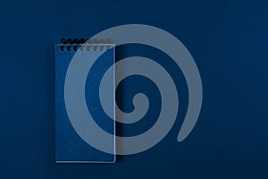 Blank page of a notebook on spiral on plain background, top view. Trendy banner with color of the year 2020 - Classic Blue