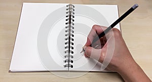 Blank Pages of Open Book with Asian Male Hand Holding Black Pencil ready to Write down photo