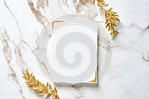 Blank paper card with golden floral branches on marble table. Wedding invitation mockup, birthday greeting card design