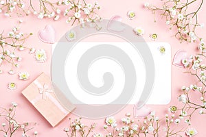 Blank paper card with gypsophila flowers and gift box on pink ba