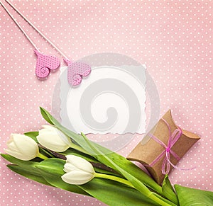 Blank paper card with white tulips, hearts and gift box on rosy