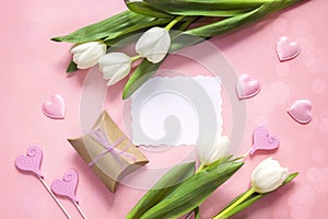Blank paper card with white tulips, hearts and gift box on rosy