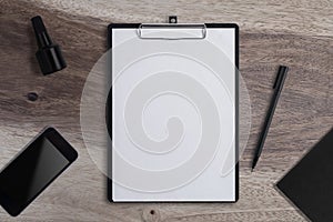 Blank Paper on Clipboard with phone and Pen  on wood table background