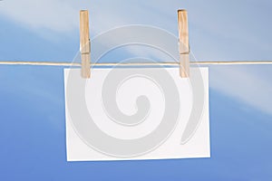 Blank paper and clothes peg on blue sky