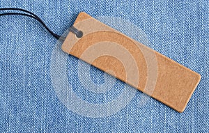 Blank paper label on a light blue denim fabric. Jeans background with sale or price tag.