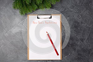 Blank paper with new year`s resolutions title and red pencil on grey table. Flat lay. Top view. New year concept. Target