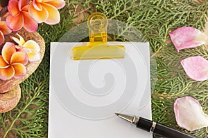 Blank paper note and pen with flowers and green leaf