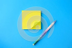 Blank paper note and pen on light blue background, flat lay