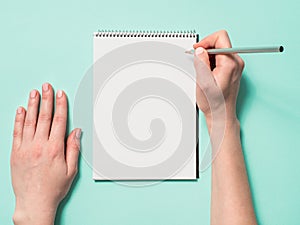 Blank paper notebook and female hands with pencil