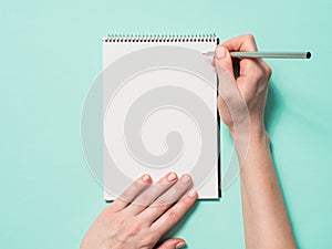 Blank paper notebook and female hands with pencil