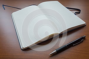 Blank paper notebook and Pencil on brown wooden table background