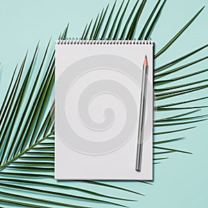 Blank paper notebook and tropical leaf