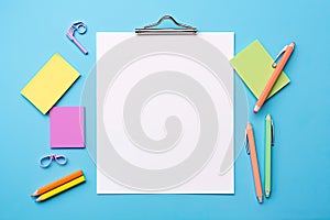 Blank paper notepad mockup with school supplies on blue background. Flat lay, top view, copy space. Back to school.