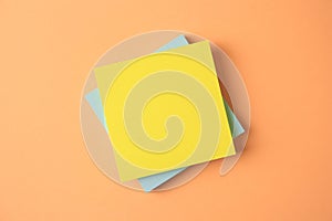 Blank paper notes on pale orange background, flat lay