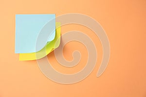 Blank paper notes on pale orange background, top view. Space for text