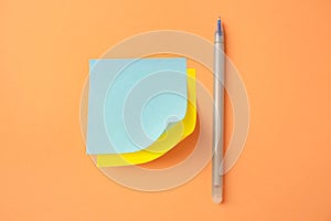 Blank paper notes and pen on pale orange background, flat lay