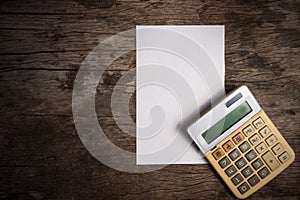 Blank paper with old calculator on wooden table.