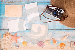 Blank paper photo frames with starfish, shells, coral and items on wooden table.