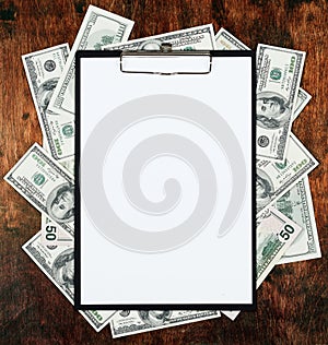 Blank paper sheet in clipboard placed on center of money dollar and old wood background. Business plan and other information conce