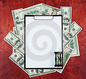 Blank paper sheet in clipboard placed on center of money dollar and wood background, sandglass, business concept and information m