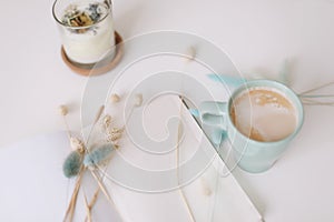 Blank paper sheet, coffee cup and dry flowers on white background. Minimal home workspace desk table. Flat lay, top view