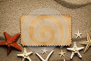 Blank paper sheet and starfishes on the beach sand