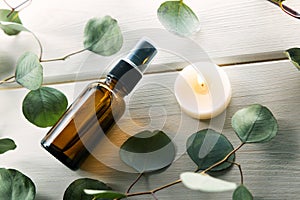 blank perfume spray bottle with eucalyptus leaves and candle on white wooden table