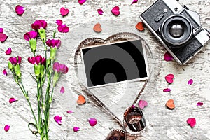 Blank photo frame in heart shaped film with retro camera and carnation flowers