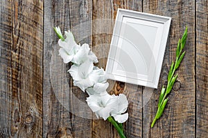 Blank photo frame near flower gladiolus on rustic wooden background top view mockup copyspace