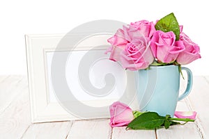 Blank photo frame and pink roses bouquet in tea cup