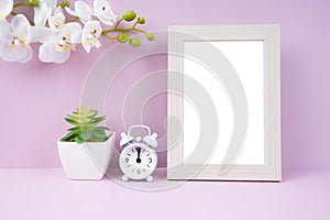 The Blank picture frame and alarm clock on pink color background with copy space and clipping path for the inside