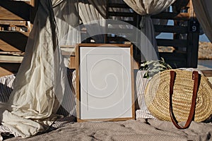 Blank picture frame, poster mockup in beach lounger, gazebo with canopy in resort at sea. Wicker straw bag with green
