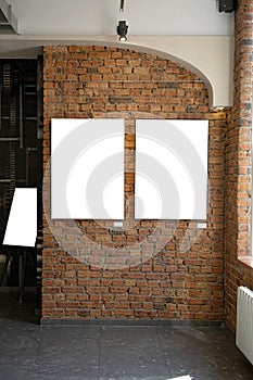 Blank picture frames on brick wall with glowing lamp, mock up