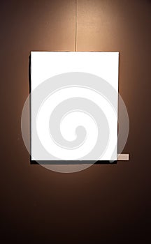 Blank picture frames on brown wall with glowing lamp, mock up