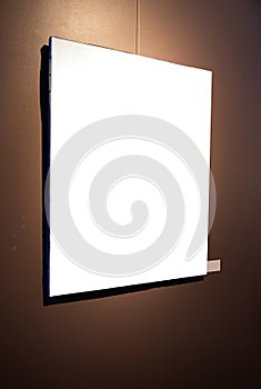 Blank picture frames on brown wall with glowing lamp, mock up