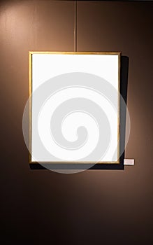 Blank picture frames on brown wall with glowing lamp, mock up