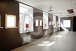 Blank picture frames on brown wall with glowing lamp, mock up