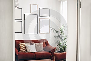 Blank picture frames mockups on white wall. White living room design. View of modern boho, scandi style interior with