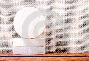 Blank piece of round wood on wood table and sack fabric wall,mock up for display your content