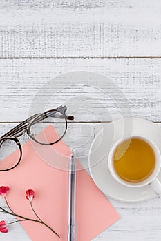 Blank pink card ,pen ,eyeglasses and a cup of tea