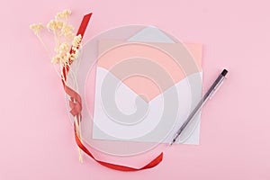 Blank pink card in white envelop and black pen