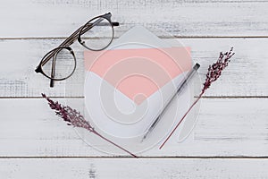 Blank pink card in white envelop, eyeglasses