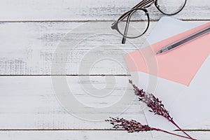 Blank pink card in white envelop, eyeglasses and black pen